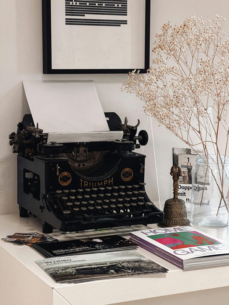 A vintage typewriter surrounded by artistic decor and magazines in a minimalist setting.