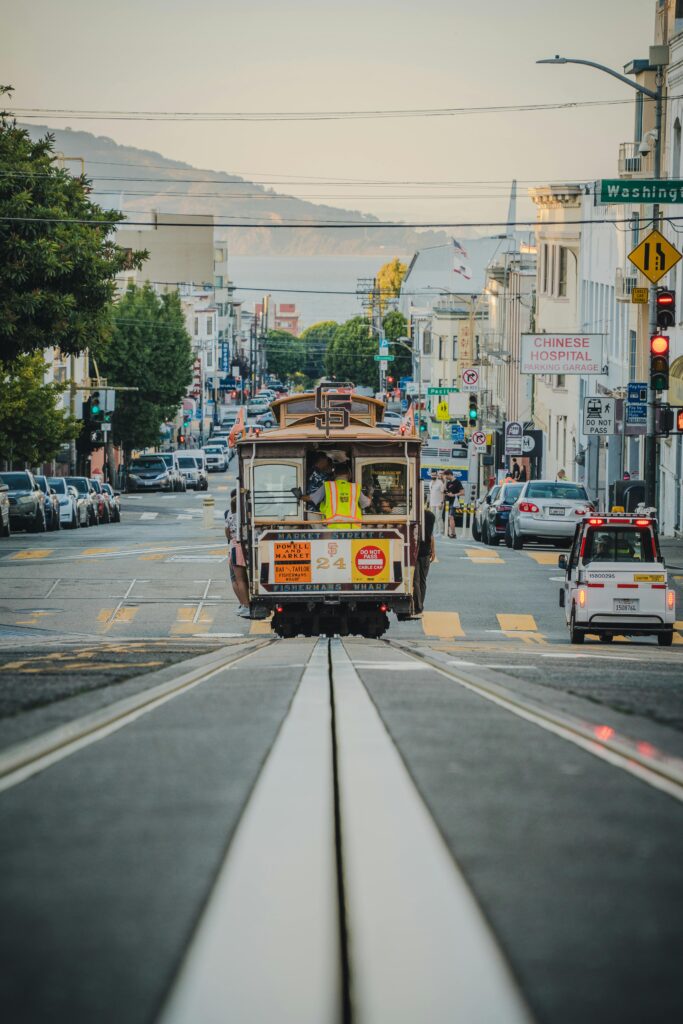 Iconic San Francisco cable car traveling uphill on a vibrant city street with a scenic backdrop.