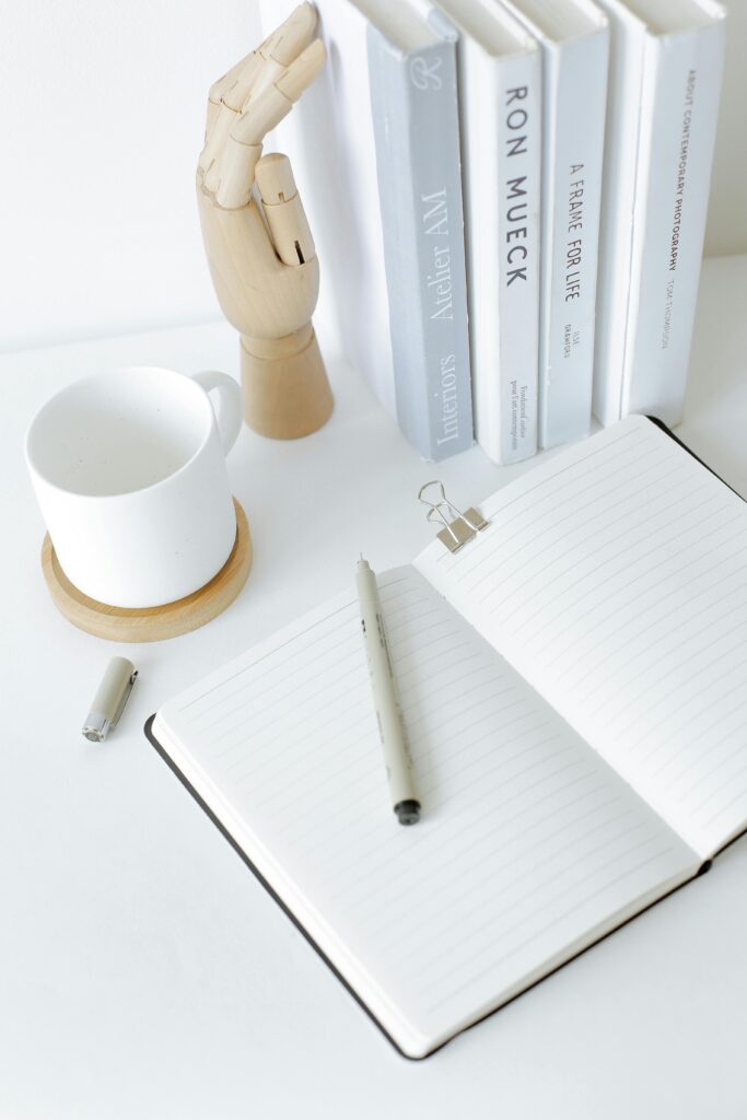 A clean and organized desk setup featuring an open notebook, books, and a mug, perfect for a modern workspace.