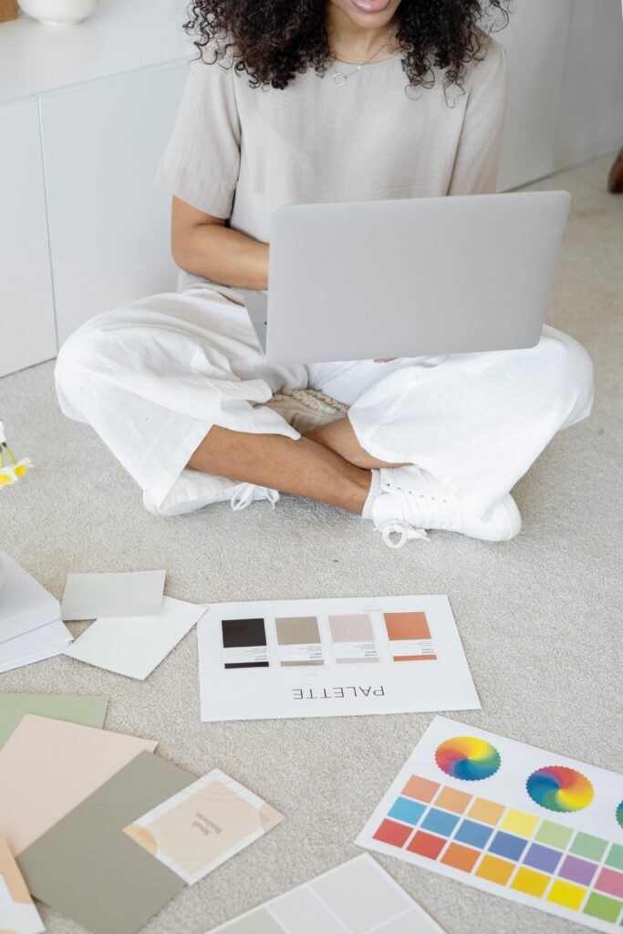 pexels-photo-7552359-7552359 Young woman reviews color palettes for design project on laptop, sitting indoors.